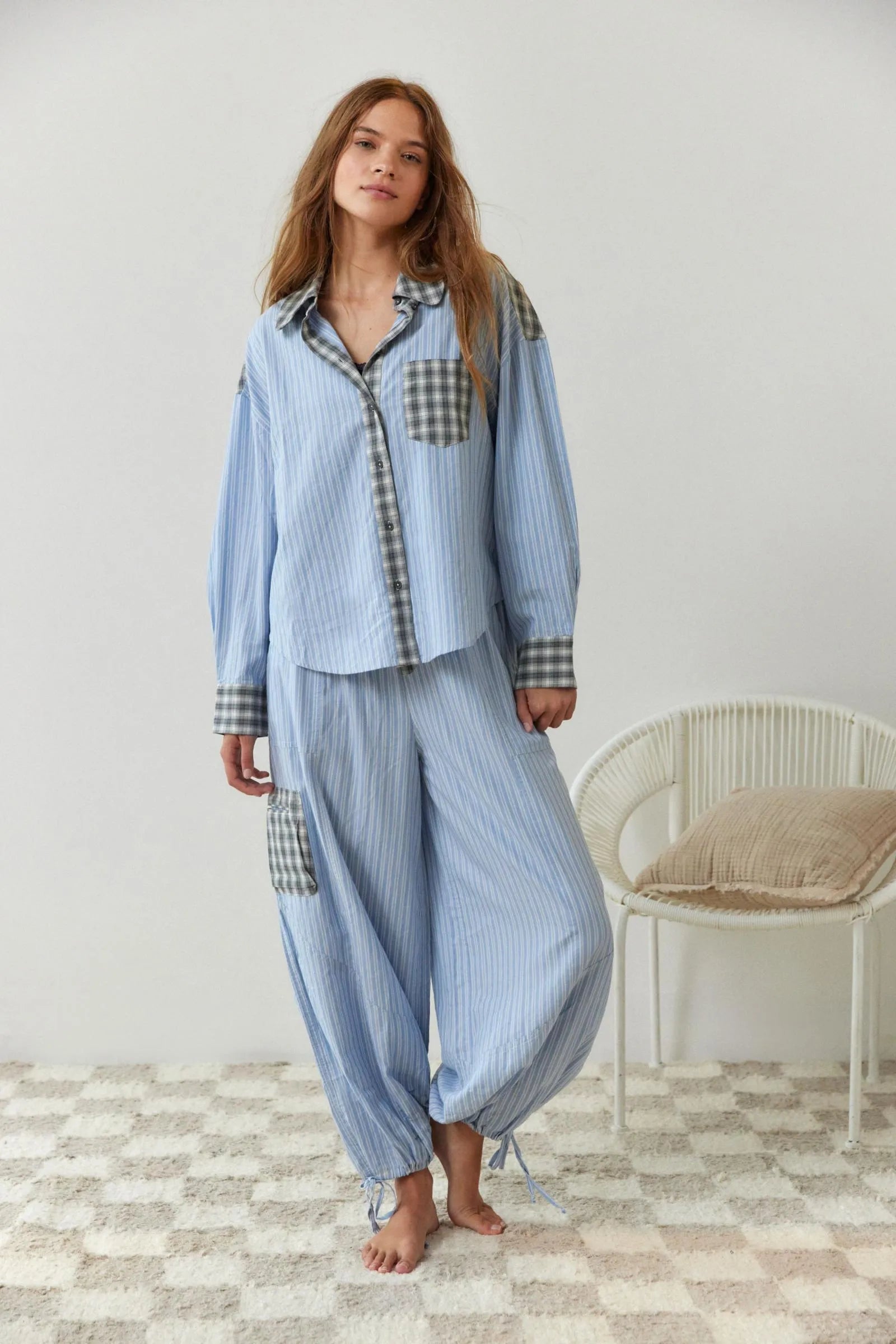 En kvinne har pĂĄ seg et 2-delt, uformelt pyjamassett med rutete design og hvit topp under