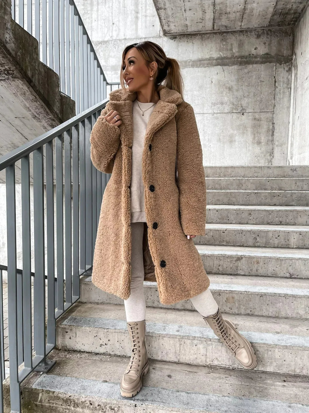 Modell iført en beige plysj trenchcoat, viser det myke stoffet og elegante snittet.