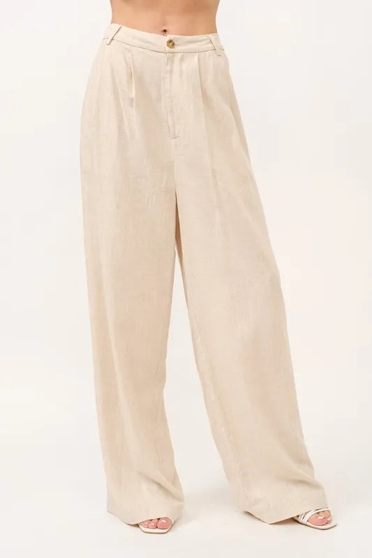 Nærbilde av beige vide bukser med høyt liv, fremhever komfortabelt stoff og elegant stil.
