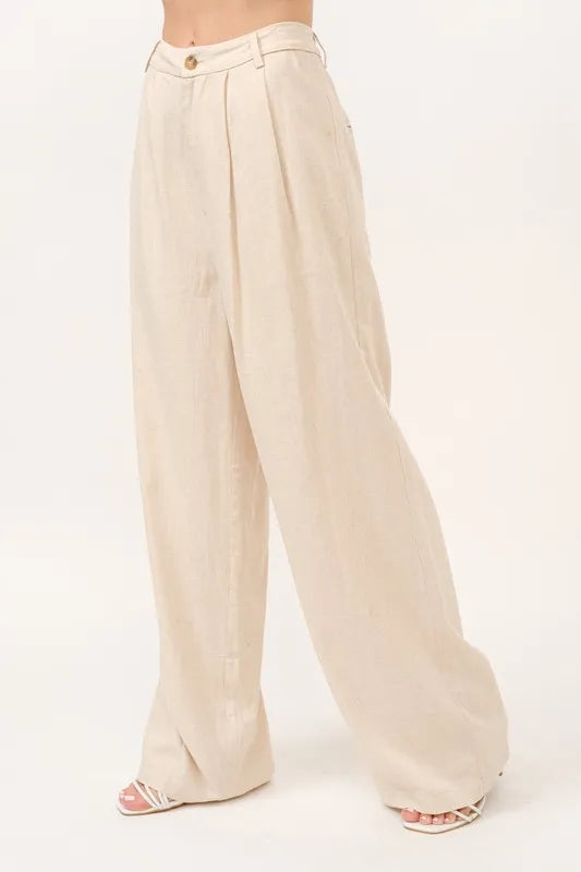 Kvinne i beige vide damebukser med høyt liv, perfekt for en casual og komfortabel sommerdag.