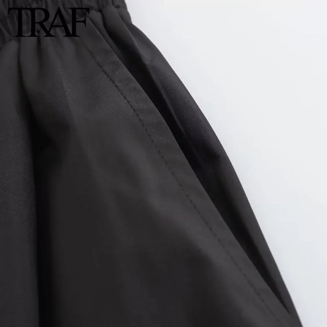 Modell iført elegant svart plissert A-linje skjørt med høy midje, perfekt for kontor og fritid.