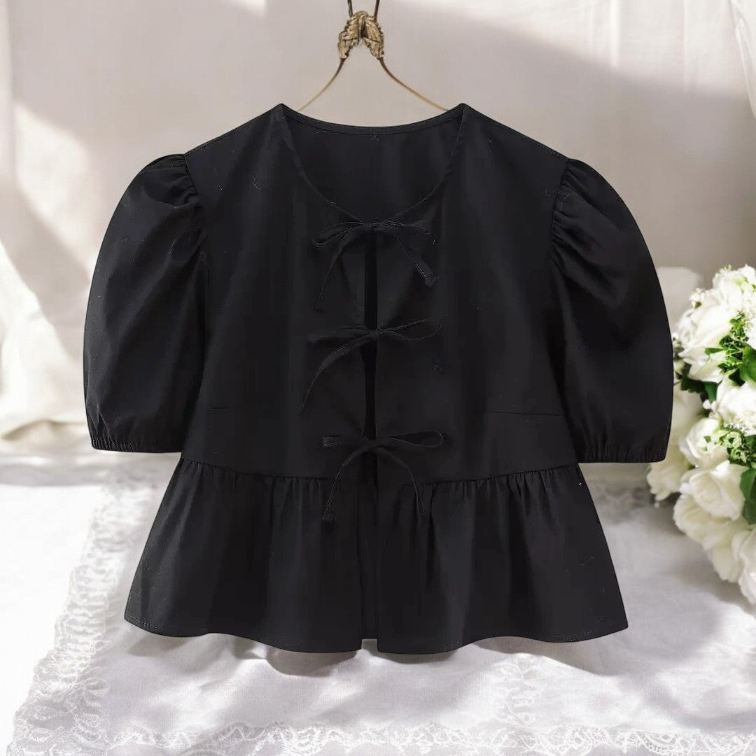 Moteriktig damebluse med feminin snøring og trendy puffermer. Passer til mange anledninger.