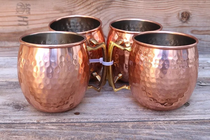 Fire skinnende kobberkopper fylt med iskalde cocktails, klar for sommerfesten på terrassen.