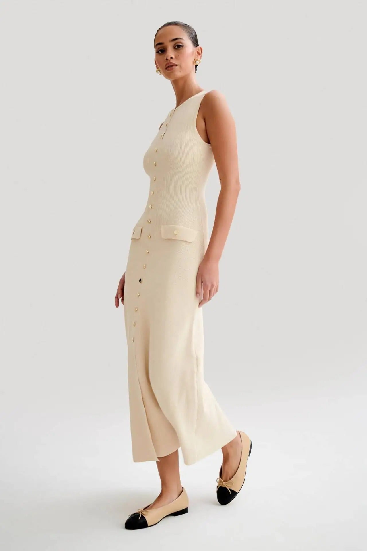 Detalj av stoffet på den ermeløse bodycon-kjolen med knapper, viser fin tekstur og det figurnære designet.