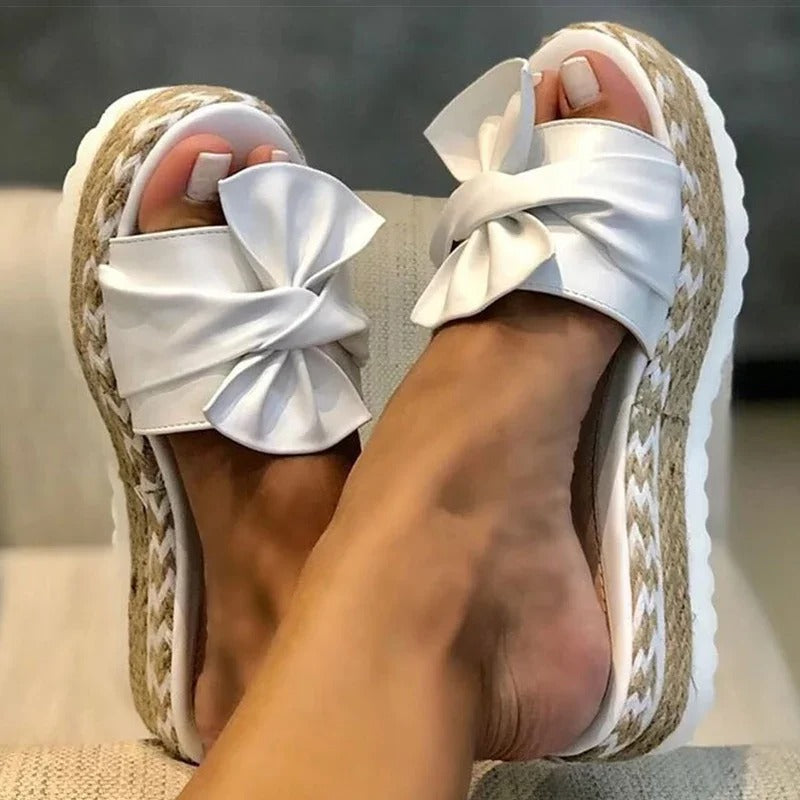 Moderne damesandaler med kileplattformhæl på fot. Komfortable slip-on platåsandaler for sommerbruk.