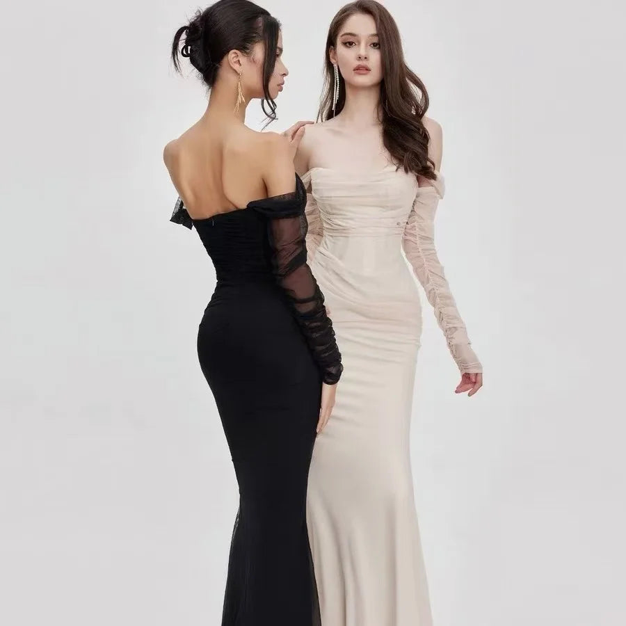 Svart formell off-shoulder havfruekjole. Figurnær kvinnekjole med elegante meshdetaljer og lange ermer.