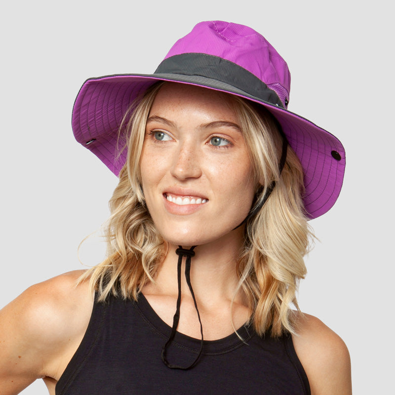 Kvinne nyter stranden med elegant, sammenleggbar UV-solhatt. Perfekt sommerhatt for solbeskyttelse.