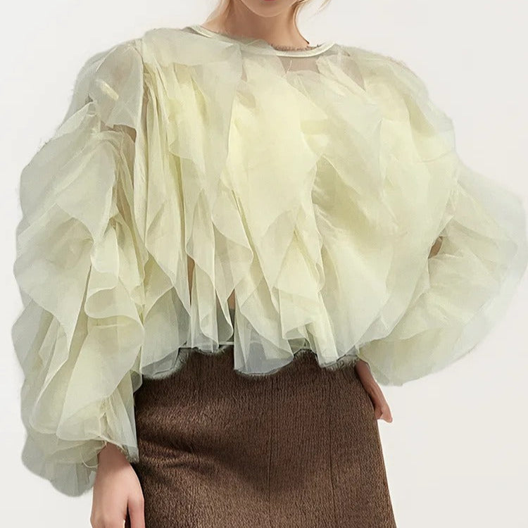 Nærbilde av delikate volangdetaljer på kvinneskjorte med O-hals. Elegant langermet bluse.