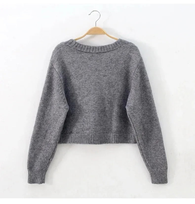 Nærbilde av aprikos strikket V-hals cardigan, viser myk tekstur og elegante detaljer.