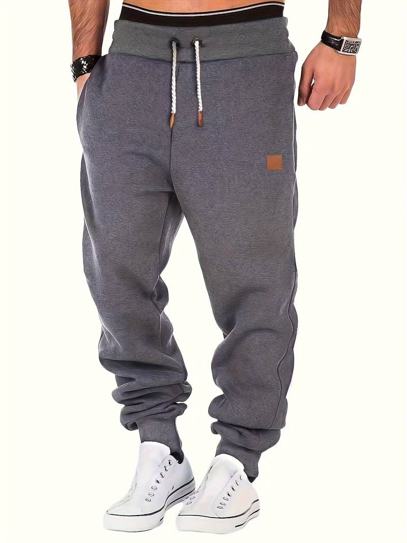 Mann iført marineblå, løstsittende joggebukse og hvit t-skjorte, avslappet stil for fritid og hverdag.