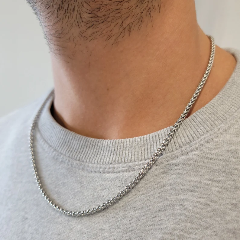 Nærbilde av elegant herre halskjede med unike krysslenker, tilgjengelig i sølv og gull utførelse.
