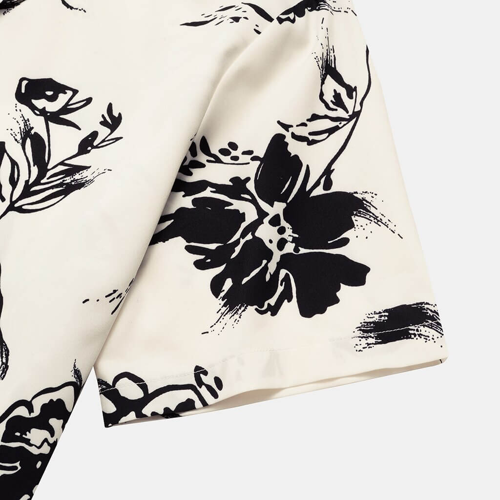 Nærbilde av beige/hvit blomstret mønster på lett menns sommerbluse. Komfortabel hawaiiskjorte for varmt vær.