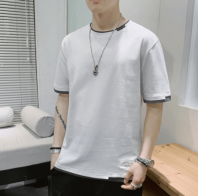 Mann i en svart oversized t-skjorte, demonstrerer den moderne og løse passformen i streetwear-stil.