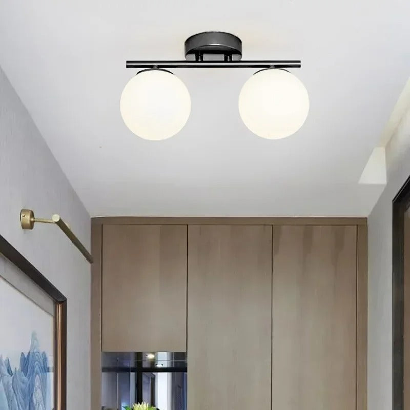 Detaljbilde av moderne glasskule taklampe med elegant gullfarget feste. Minimalistisk design.