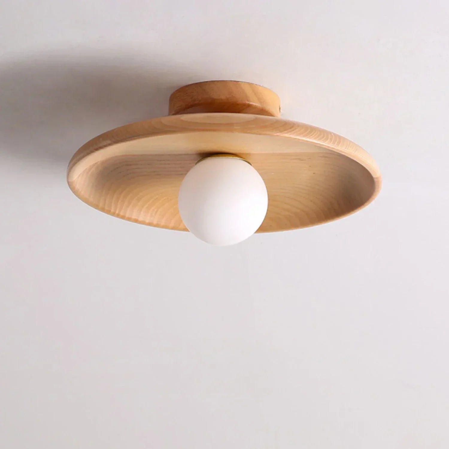 Detalj av kuleformet tre taklampe. Viser naturlig trestruktur og nordisk design, skaper varm innendørs belysning.