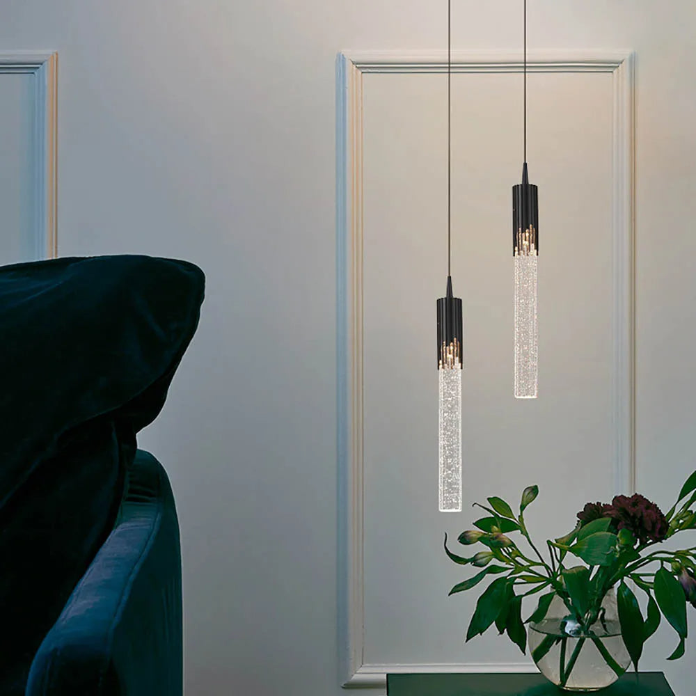 Sylinderformet glasslampe, gir stilfull og varm belysning over spisebord i moderne hjem.