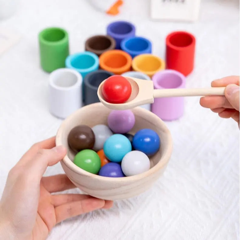 Montessori sett med 6 fargede trekopper og matchende regnbueballer, for utviklingslek og fargelæring.