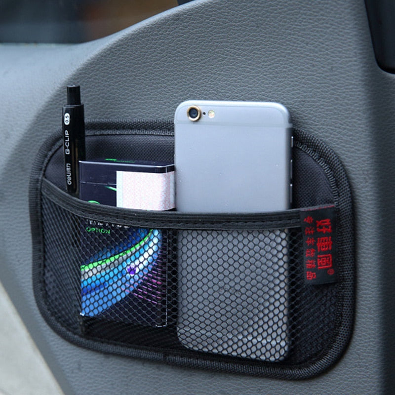 Detaljbilde av skinnnett bilorganisator festet i bil, viser hvordan den holder telefon og lommebok.