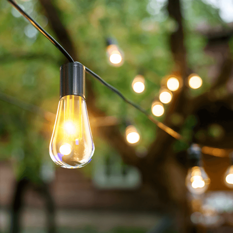 Lysende LED-lyslenke i hagen om natten, drevet av solenergi, for stemningsfullt lys.