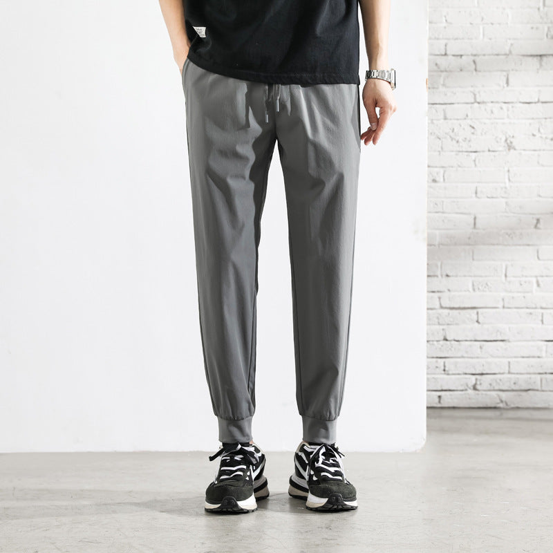 Grå tapered joggebukser for menn med elastisk midje og glidelåslommer, ideelle som fritidsbukser.