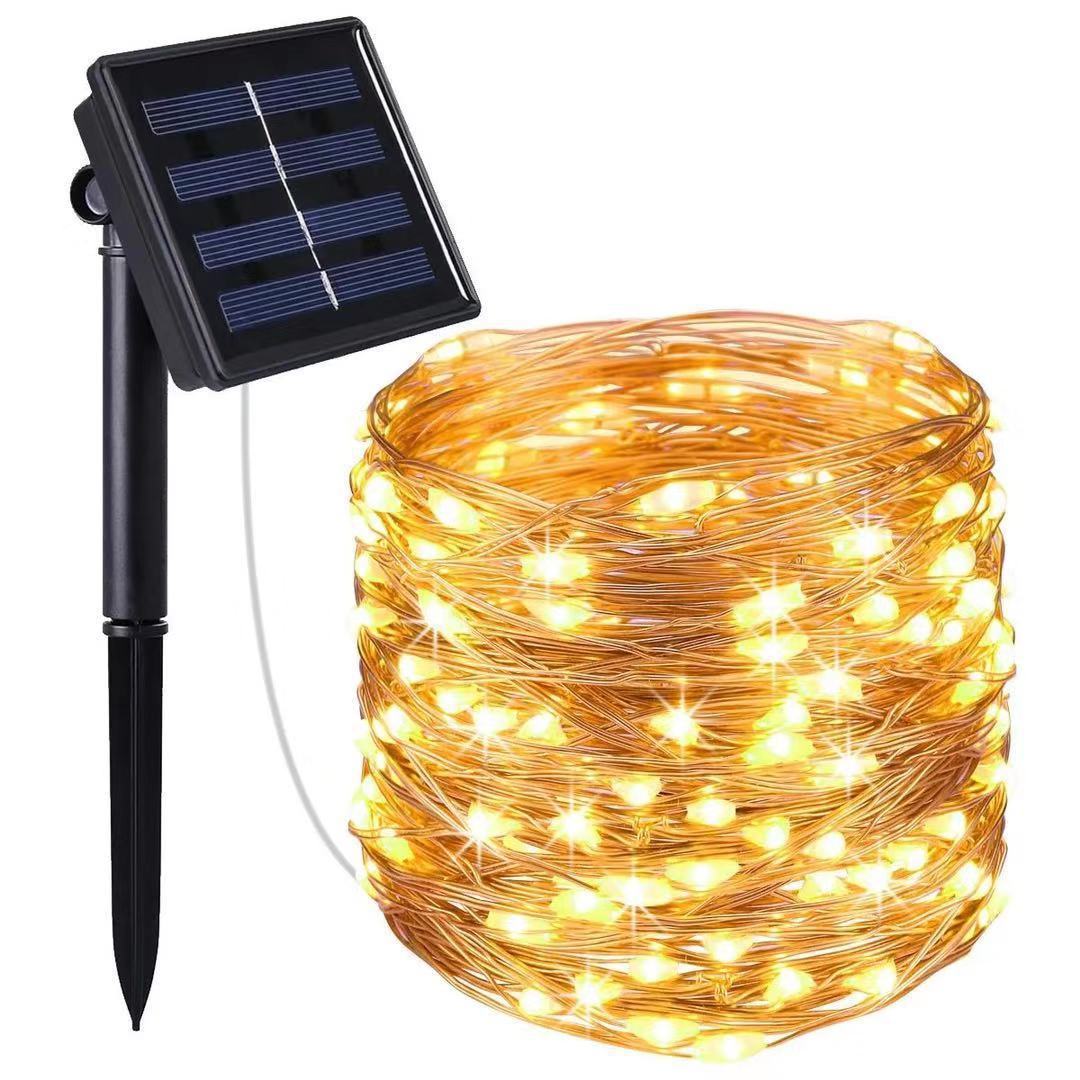 Nærbilde av glødende pærer på en solenergi lysstreng i skumringen, forbedrer hagens utseende.