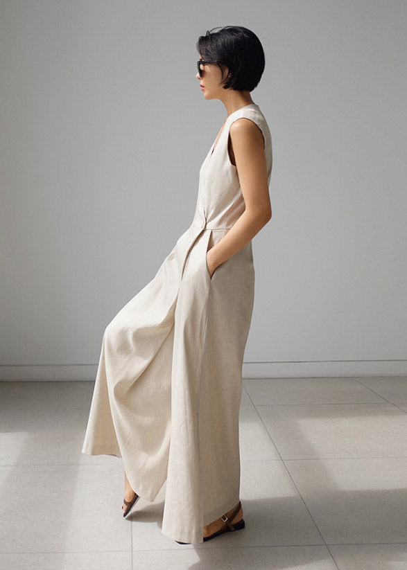 Løs beige damejumpsuit med V-hals og praktiske knapplommer, flott for sommeren.