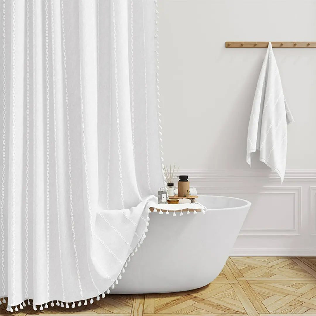 Teksturert boho dusjforheng med håndlagde dusker, gir varme og stil til baderomsdesignet.