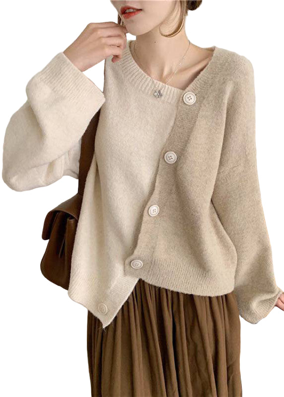 Dame asymmetrisk strikket vintergenser i beige. Komfortabel og varm genser med moderne snitt og knappdetaljer.