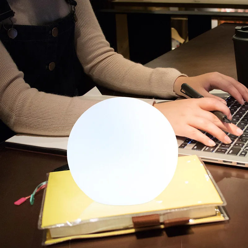 Nærbilde av Dynamisk LED kulebordlampe som viser mykt, fargeendrende lys, en moderne stemningslampe.