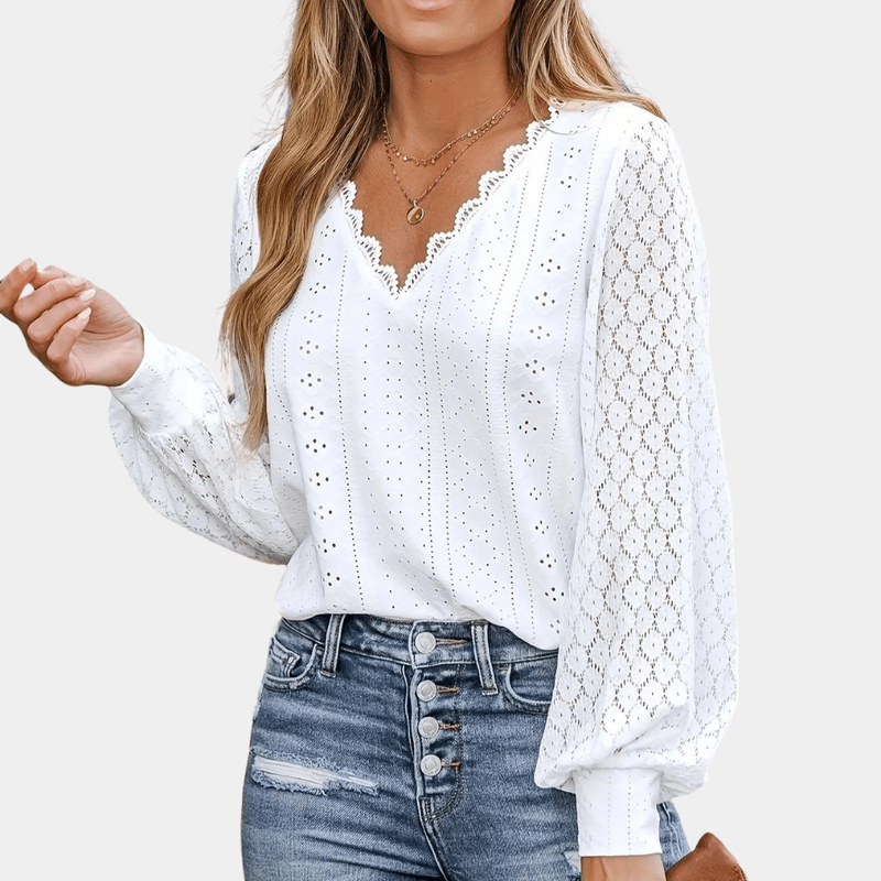 Detaljert bilde av V-halsen på en elegant damebluse med intrikate blonder. Moderne festtopp.