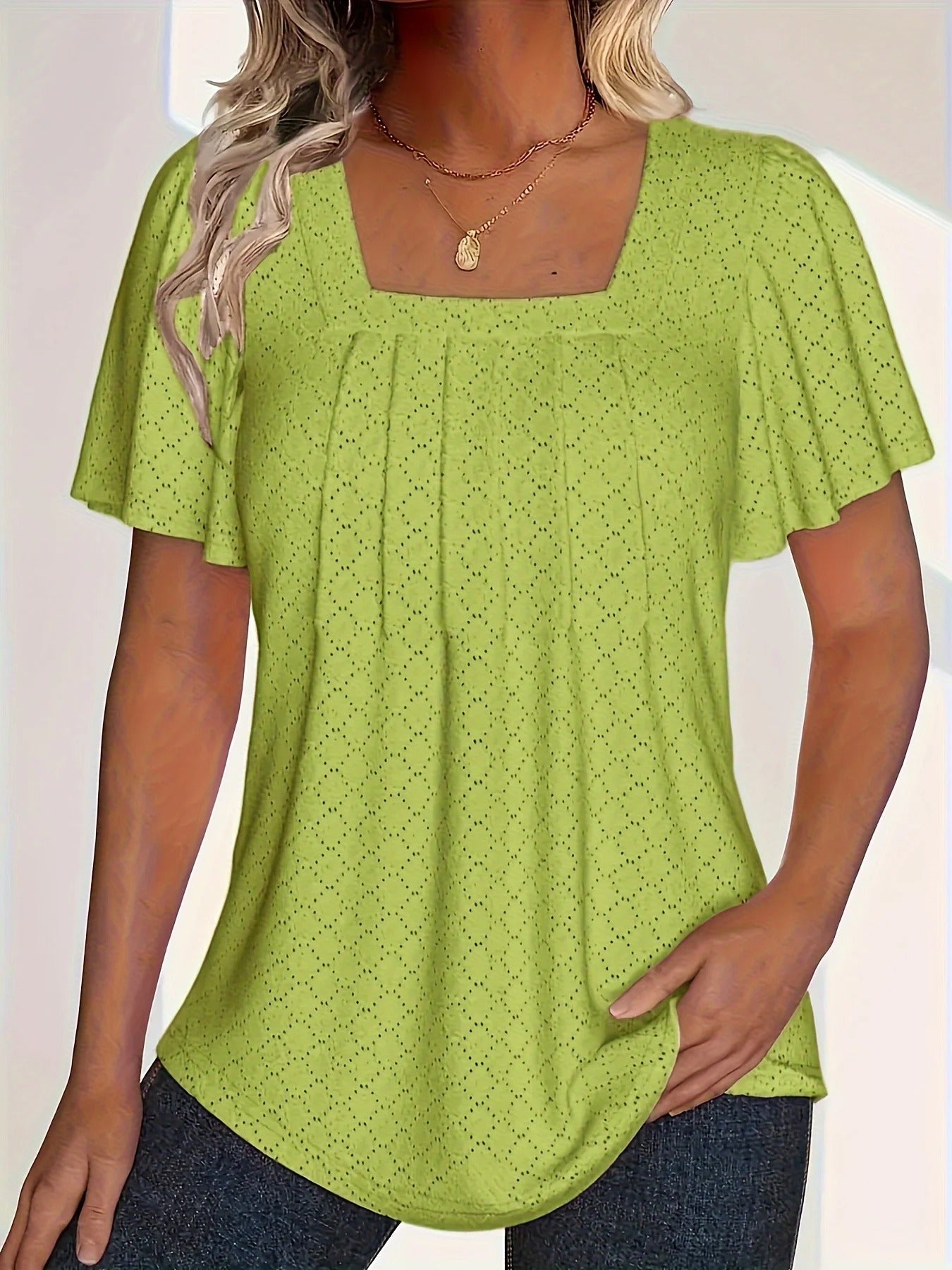 Nærbilde av feminin damebluse. Viser volanger og delikate hulldetaljer. Perfekt sommer- eller kontorbluse.