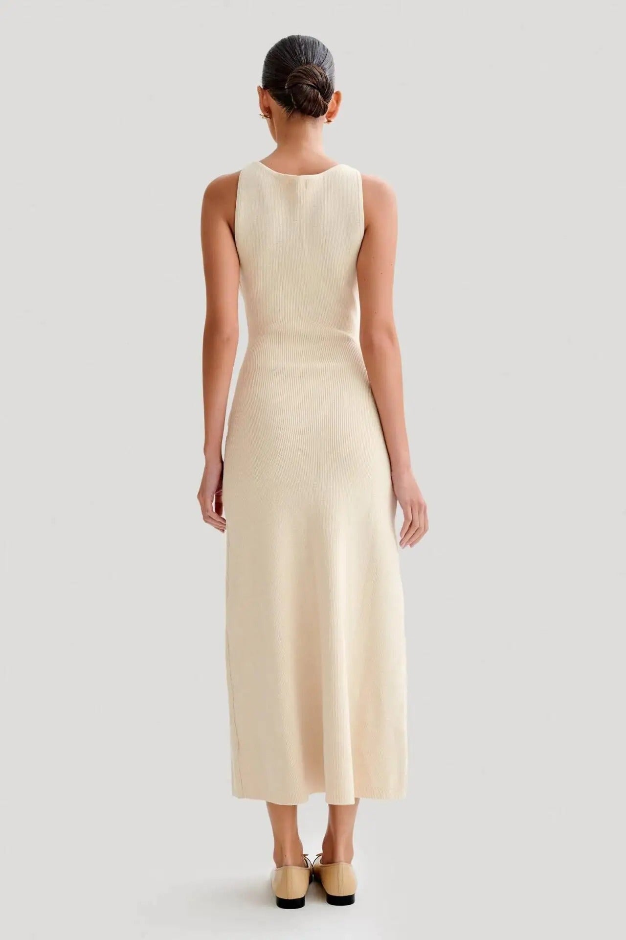 Stilfull kvinne i elegant ermeløs bodycon-kjole med knapper, perfekt som aprikos festkjole eller blå sommerkjole.