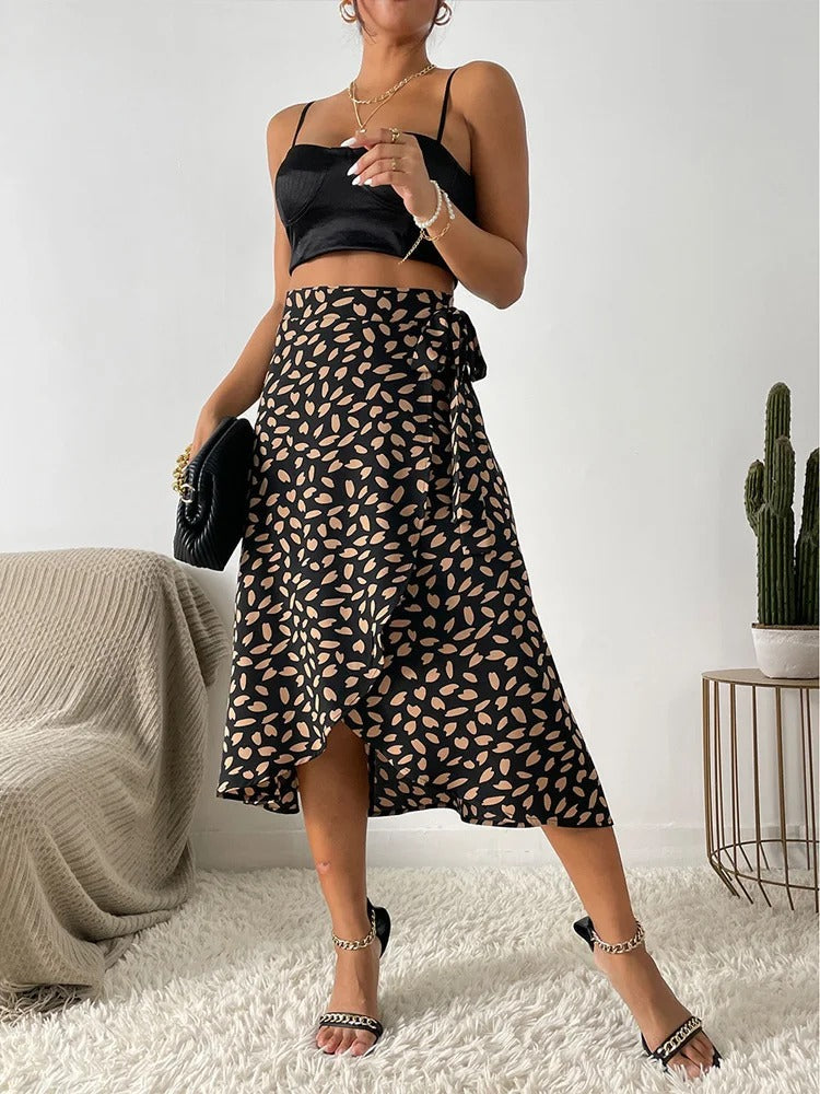 Kvinne iført et elegant, asymmetrisk wrapskjørt med høymidje og bindebånd på siden. Trendy sommermote.