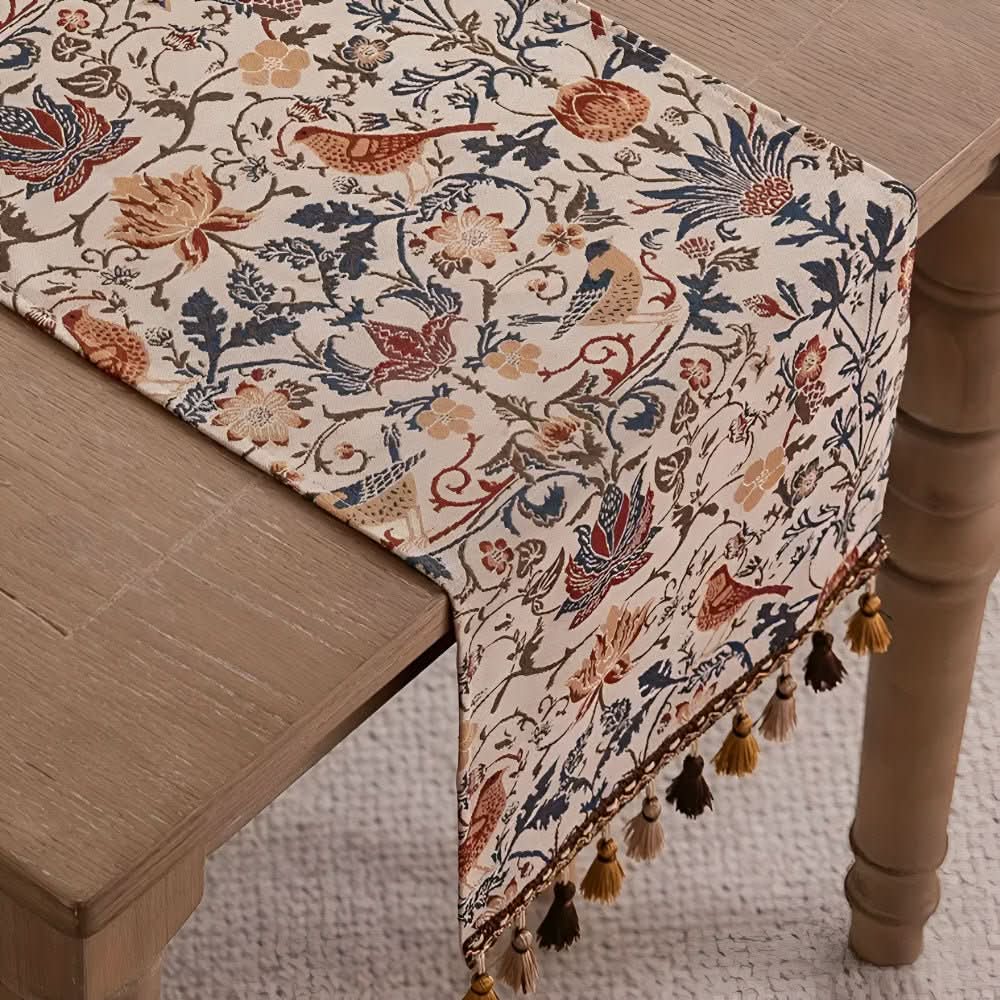 Spisebord dekket med elegant bordløper. Viser blomster- og fuglemotiv, skaper rustikk og vintage stemning.
