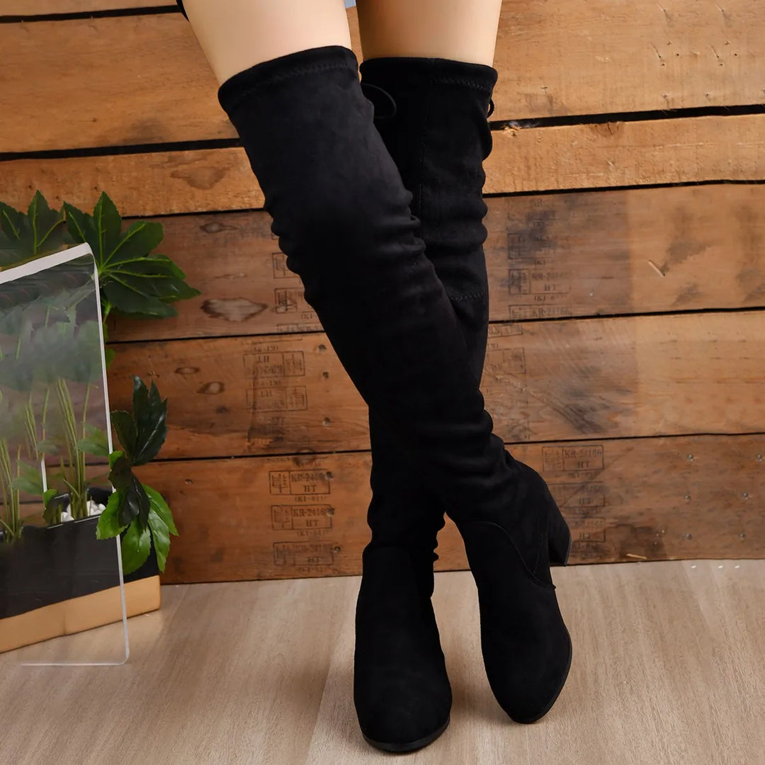 Nærbilde av spiss tå og robust blokkhæl på elegante over-the-knee kvinneboots. Komfortabelt og stilrent.