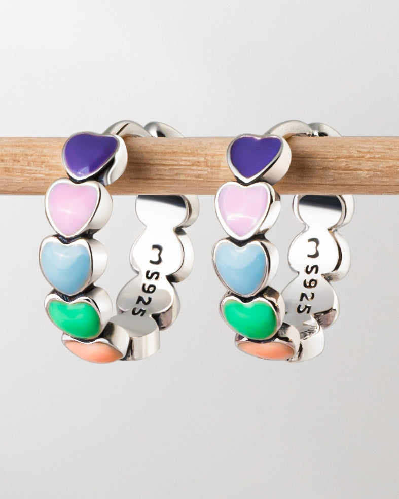 Nærbilde av fargerike hjerte øredobber i sølv og gull, en vakker gaveidé for dame.