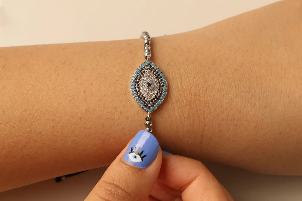 Dame armbånd med onde øye symbol, elegant båret på håndleddet. Et moderne smykke for beskyttelse og personlig stil.