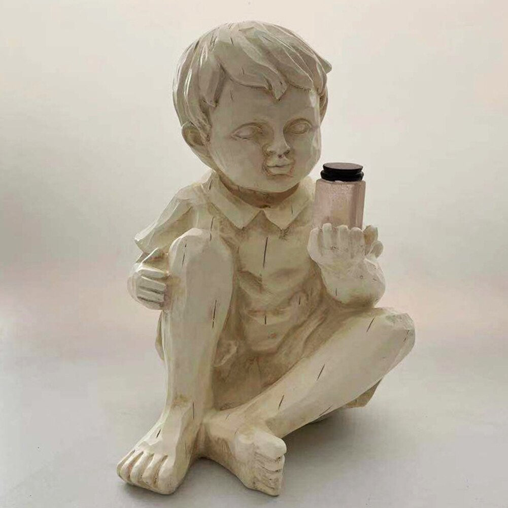 Barnefigur hagestatue i resin, med solcellelys som etterligner ildfluer om natten.