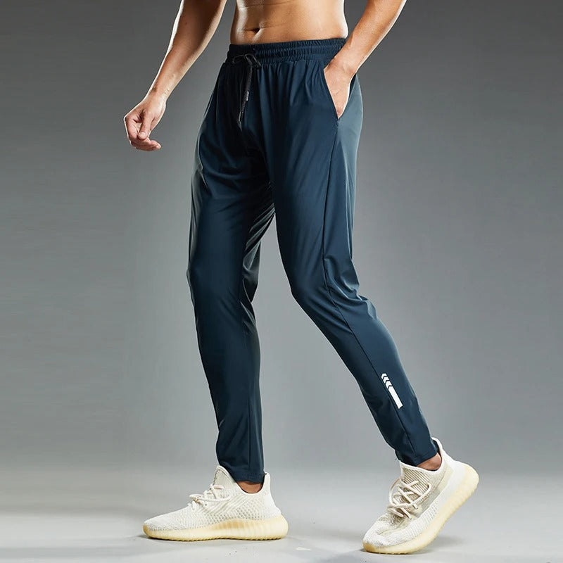 Atletisk mann i sorte joggebukser strekker. Perfekt for aktiv trening, sport og komfortabel fritid.