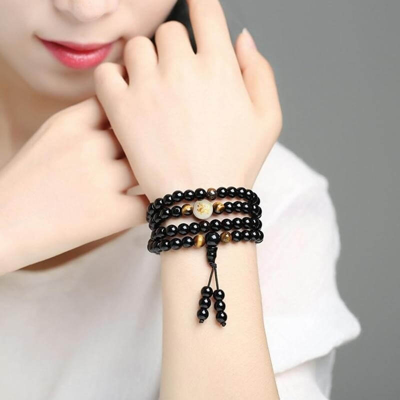 Detaljbilde av lysende drage og glatt obsidian naturstein på armbåndet, unisex.