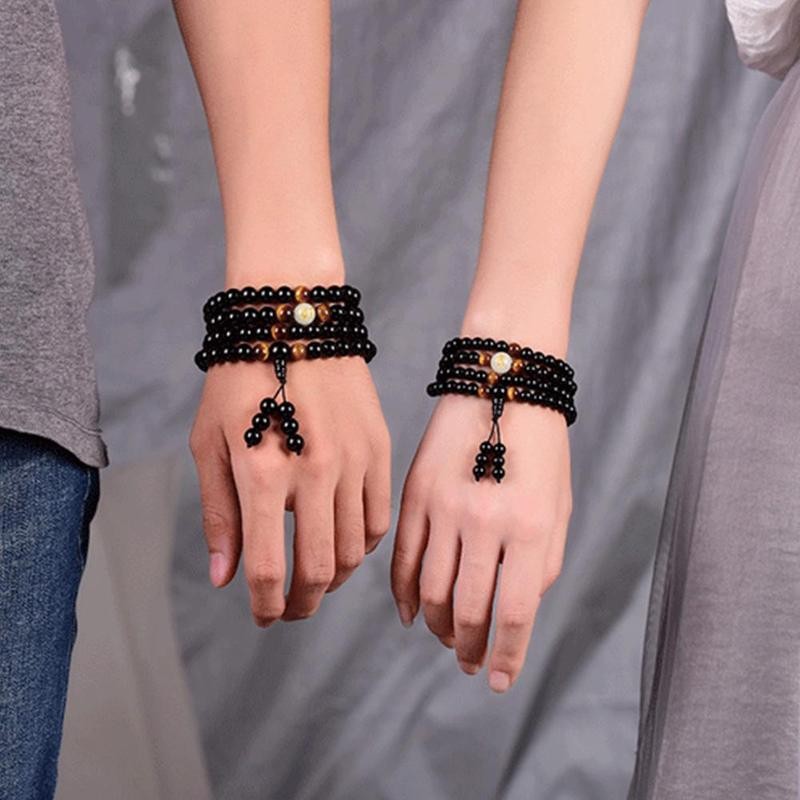 Nærbilde av skinnende drage på armbånd med polert obsidian naturstein perler.