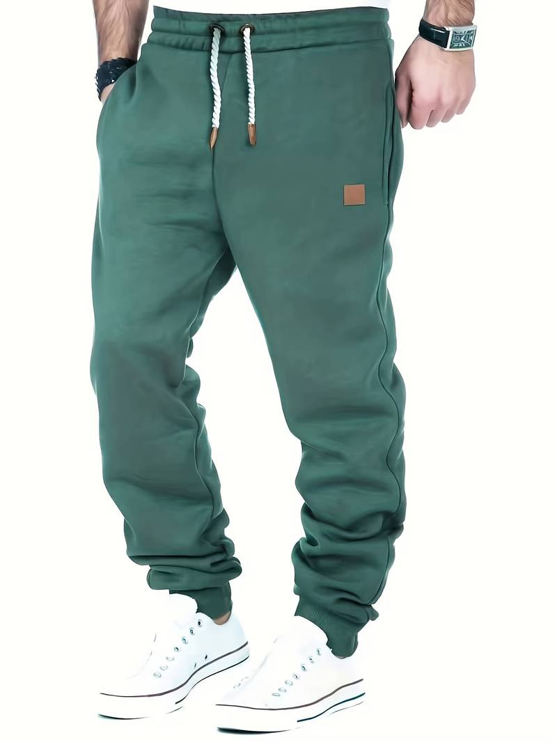 Stilfull, løstsittende joggebukse for menn i marineblå, med elastisk linning og ribbestrikkede mansjetter.