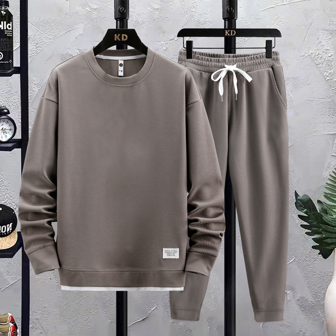 Ung mann iført flerfarget joggedress. Trendy sporty stil, perfekt for fritid og aktivitet.