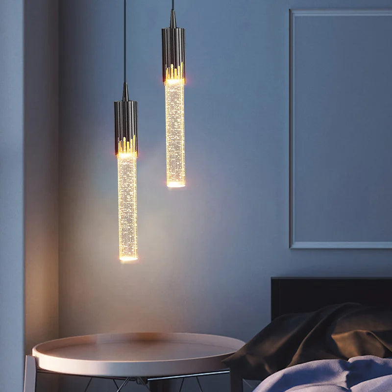 Minimalistisk sylindrisk glasslampe i svart og gull, skaper koselig stemning i stuen.