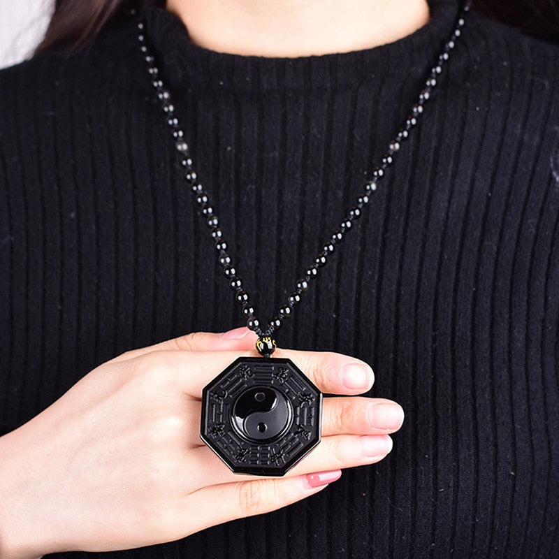 Detaljert bilde av det polerte obsidian Yin Yang anhenget, som reflekterer lys.