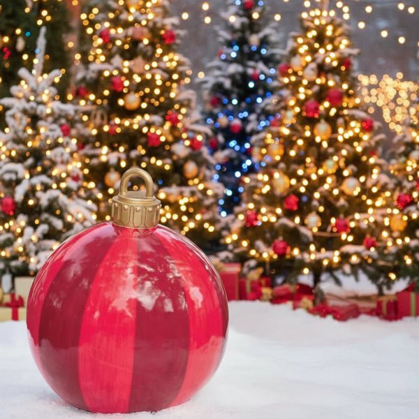 Store oppblåsbare julekuler plassert i snødekket hage om dagen. Magisk utendørs juledekorasjon for vinteren.