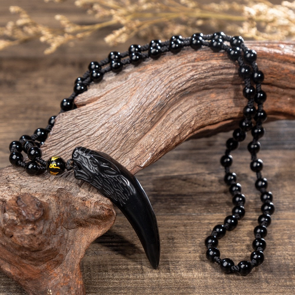 Nært bilde av kraftfullt obsidian ulv anheng på kjede. Unisex smykke for styrke og beskyttelse.