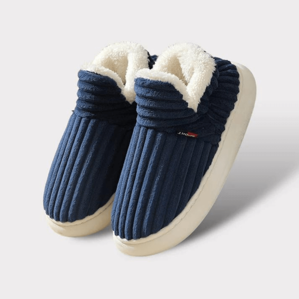 Et par grå unisex plysjtøfler med antiskli såle, klar for komfortabel bruk hjemme.