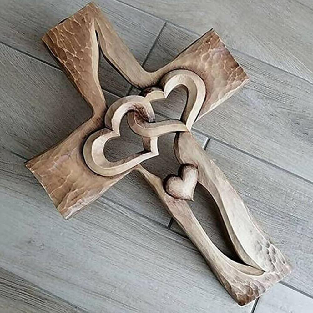 Nærbilde av detaljert utskåret trekors med to sammenflettede hjerter. Religiøs, håndlaget veggdekor.