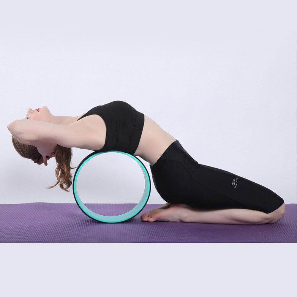 Kvinne demonstrerer ryggstrekk og fleksibilitet med et yogahjul under en yogasesjon.
